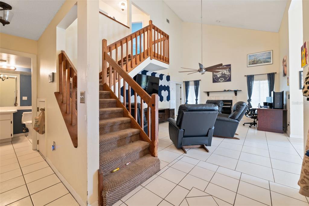 A living room with a carpeted staircase, tiled floors, and a vaulted ceiling — 24138 TWIN COURT, LAND O LAKES, FL