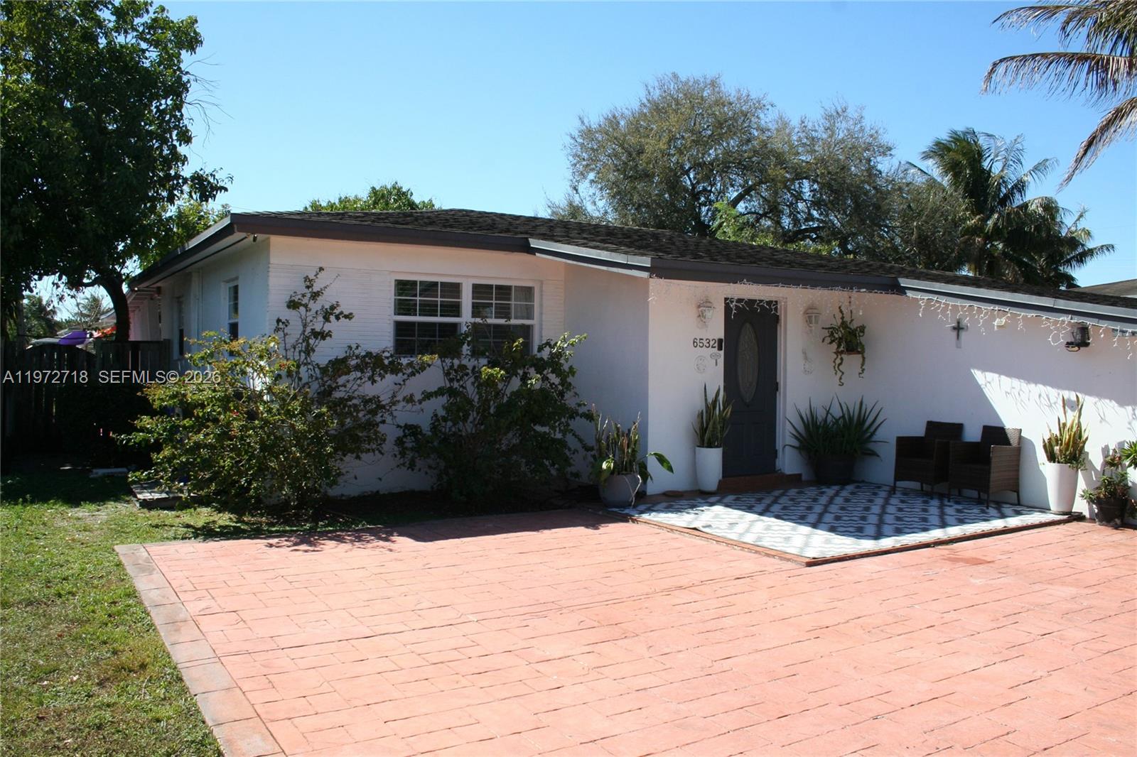 A single-story white house features a brick-paved driveway and a small front patio area — 6532 Mayo St, Hollywood FL 33023, HOLLYWOOD, FL