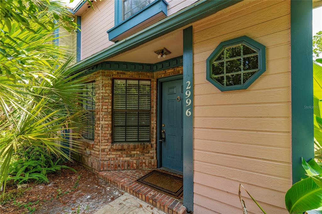 The exterior entrance features a blue door, brick siding, and an octagonal window — 2996 LOWELL COURT, CASSELBERRY, FL