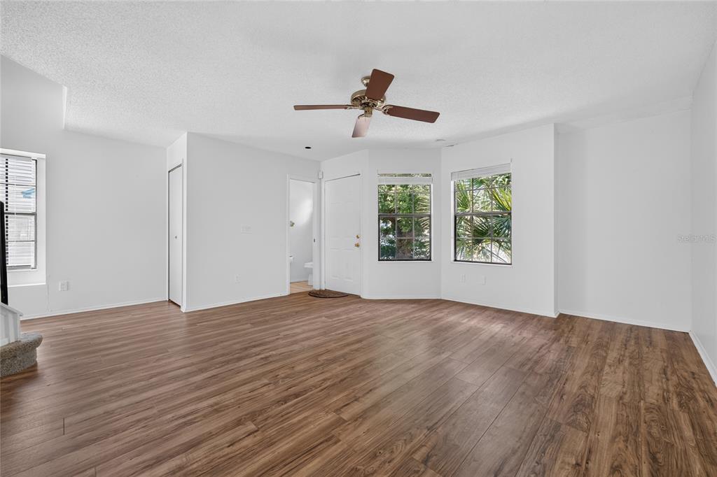 A living room with white walls, wood-look flooring, a ceiling fan, and two windows — 2996 LOWELL COURT, CASSELBERRY, FL