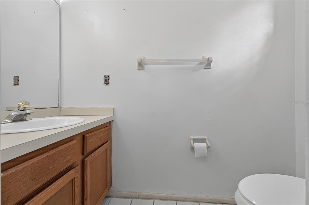 A bathroom features a wooden vanity with a white sink, a towel bar, and toilet — 2996 LOWELL COURT, CASSELBERRY, FL