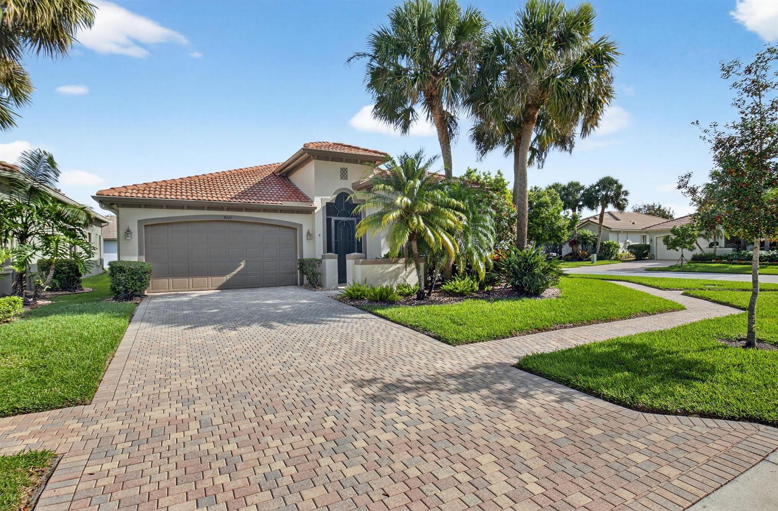A single-story house with a tiled roof, a paved driveway, and palm trees in front — 9571 Isles Cay Drive, Delray Beach FL 33446, DELRAY BEACH, FL