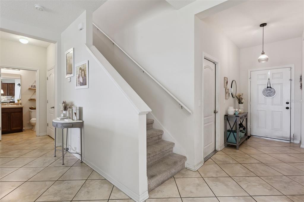 A bright entryway features a carpeted staircase, tiled floors, and a front door — 2514 PLUMADORE DRIVE, GRAND ISLAND, FL