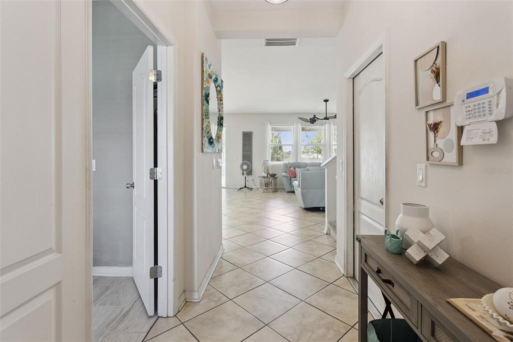 A hallway with tile flooring leads to a living area with light blue furniture — 2514 PLUMADORE DRIVE, GRAND ISLAND, FL
