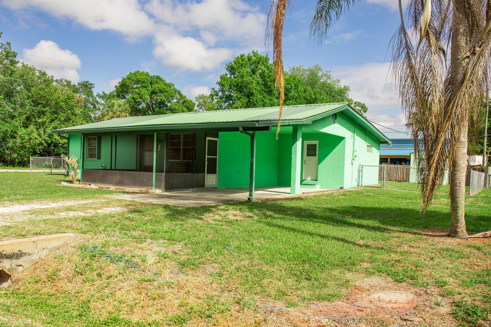 A bright green, single-story house with a metal roof and a covered front porch — 1120 SW 8th Court, Okeechobee FL 34974, OKEECHOBEE, FL