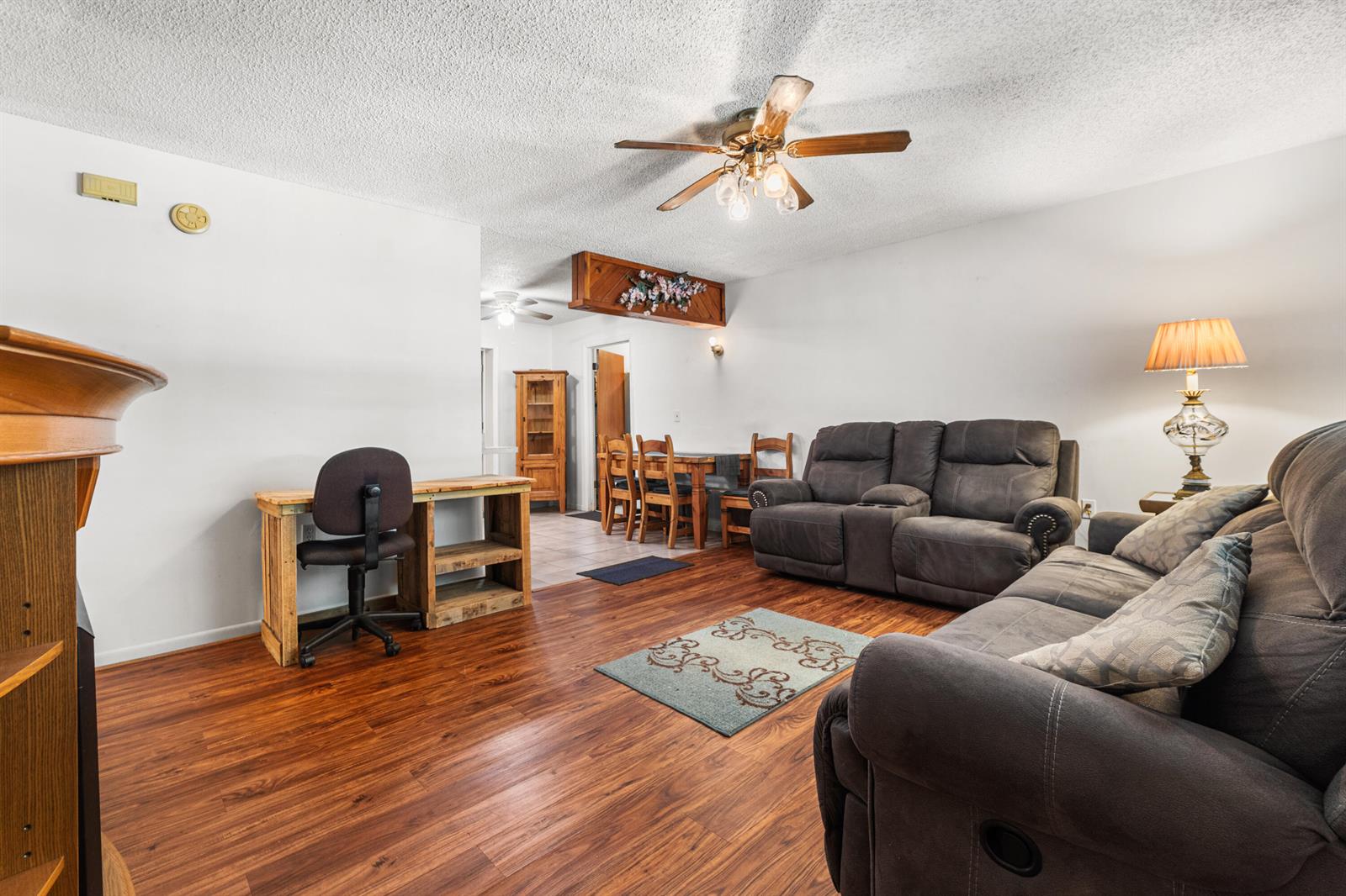A living room features wood-look flooring, a ceiling fan, and a desk area near a dining space — 1120 SW 8th Court, Okeechobee FL 34974, OKEECHOBEE, FL