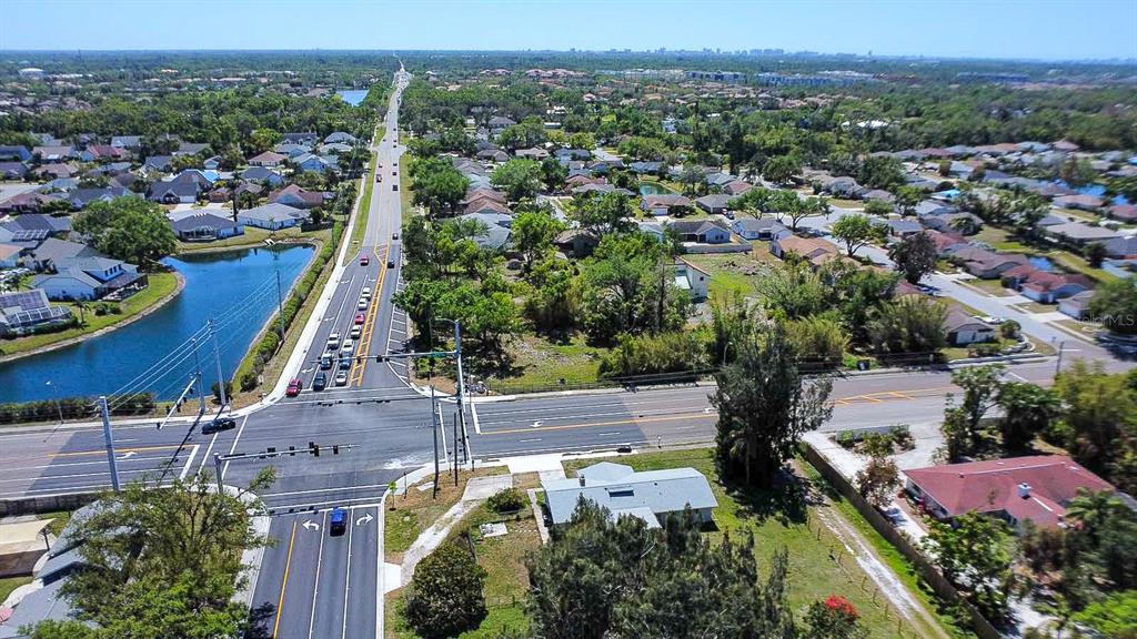 An aerial view shows a suburban intersection with residential homes, a pond, and roads — 7720 TUTTLE AVENUE, SARASOTA, FL