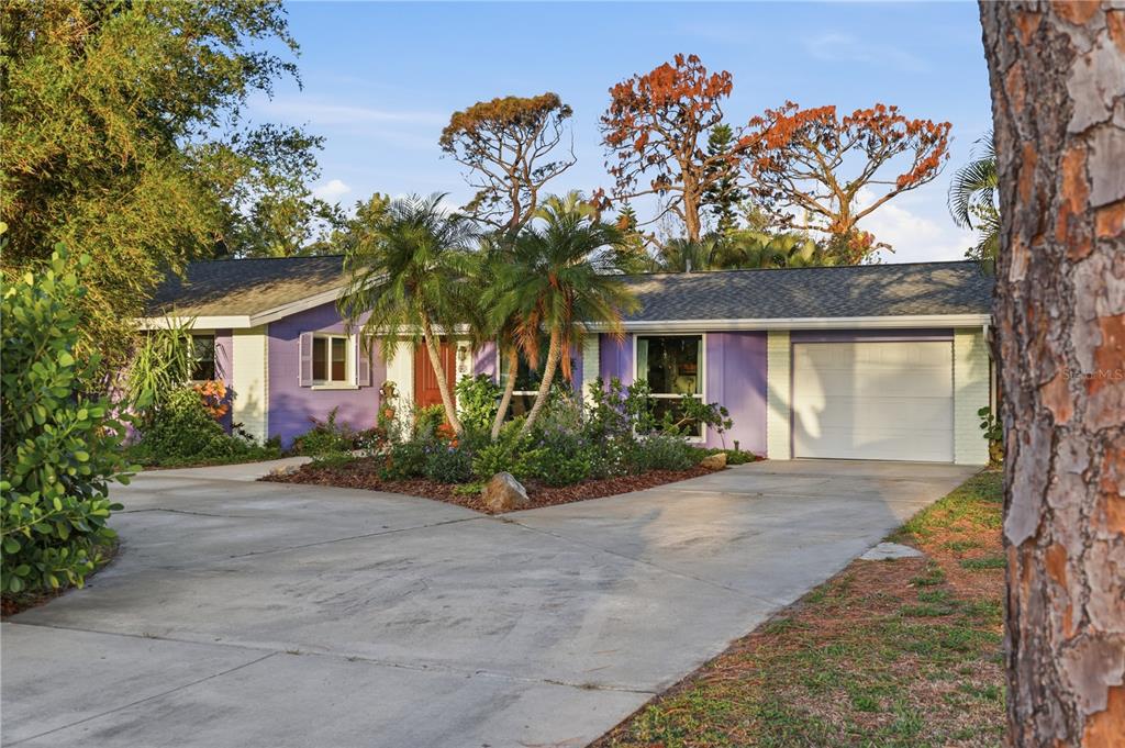 A single-story house with purple exterior walls, a white garage door, and a concrete driveway — 1620 MANOR ROAD, ENGLEWOOD, FL