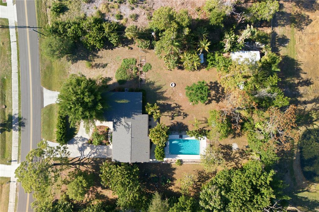 An aerial view shows a house with a swimming pool and yard surrounded by trees — 1620 MANOR ROAD, ENGLEWOOD, FL