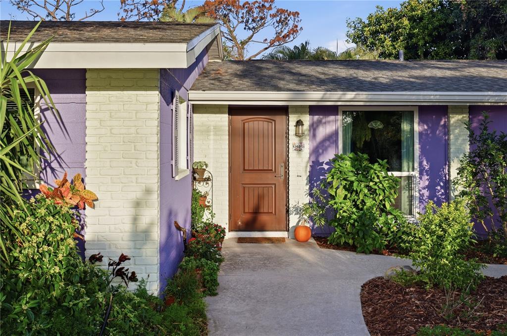 The exterior of a house features purple walls, white brick accents, and a brown front door — 1620 MANOR ROAD, ENGLEWOOD, FL