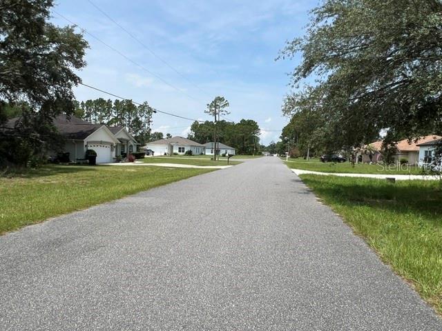 A paved residential street lined with single-family homes and mature trees under a blue sky — Lot 2 SW 132 STREET, OCALA, FL
