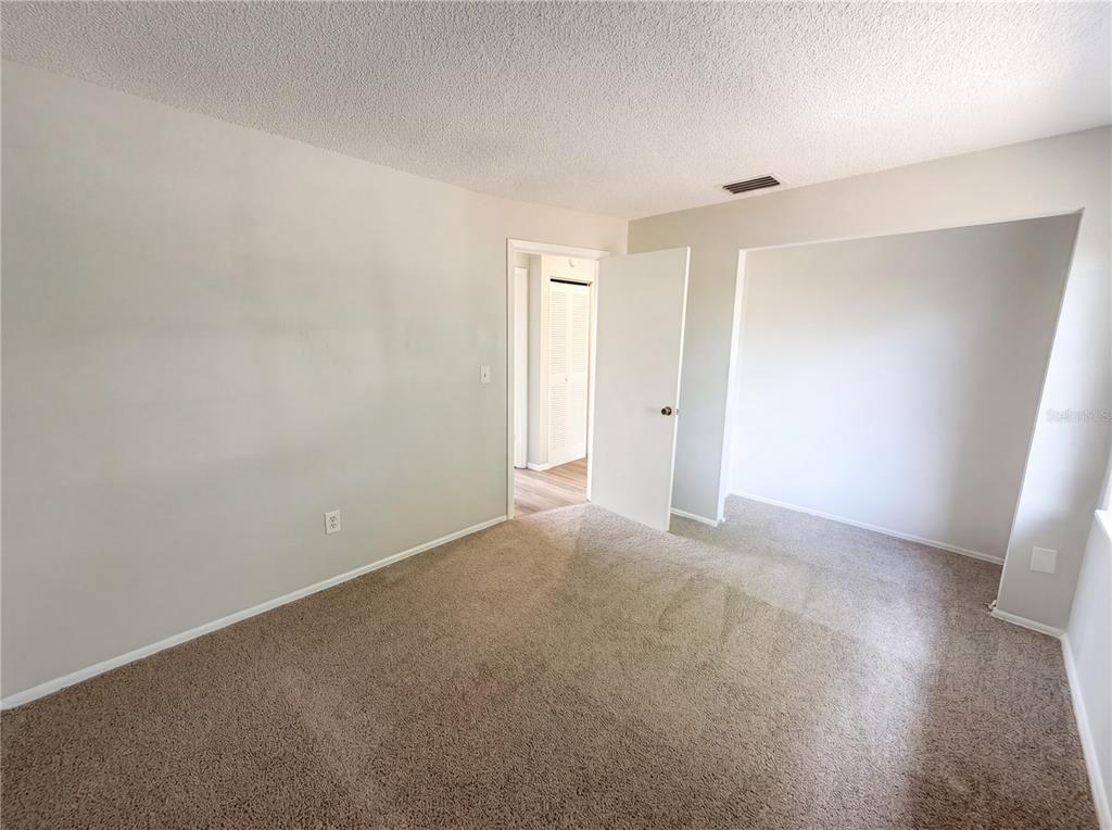 An empty bedroom features beige carpet, light gray walls, and an open doorway — 3130 LUDLOW DRIVE, NEW PORT RICHEY, FL