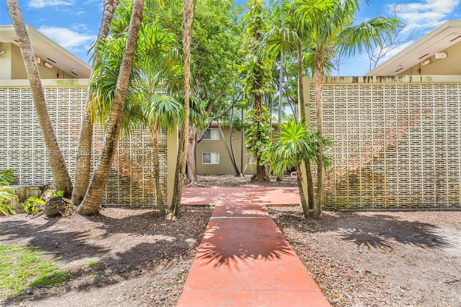 A red concrete walkway leads between two buildings with decorative breeze block privacy walls — 6330 SW 79th St # 2, South Miami FL 33143, SOUTH MIAMI, FL