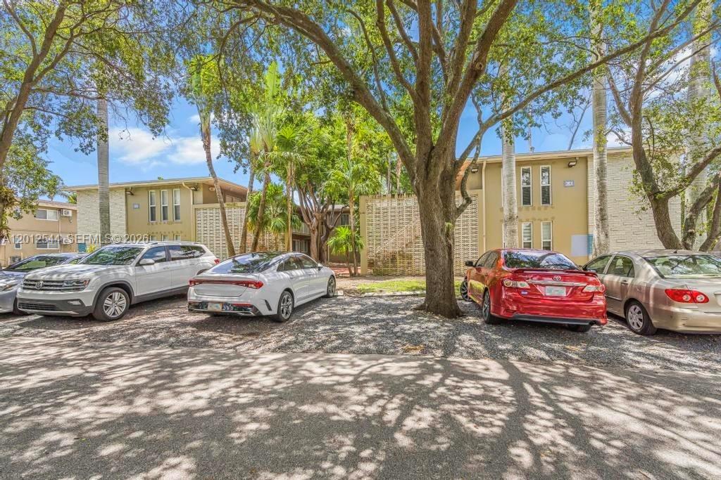 A gravel parking lot sits in front of a two-story apartment building with trees — 6330 SW 79th St # 2, South Miami FL 33143, SOUTH MIAMI, FL