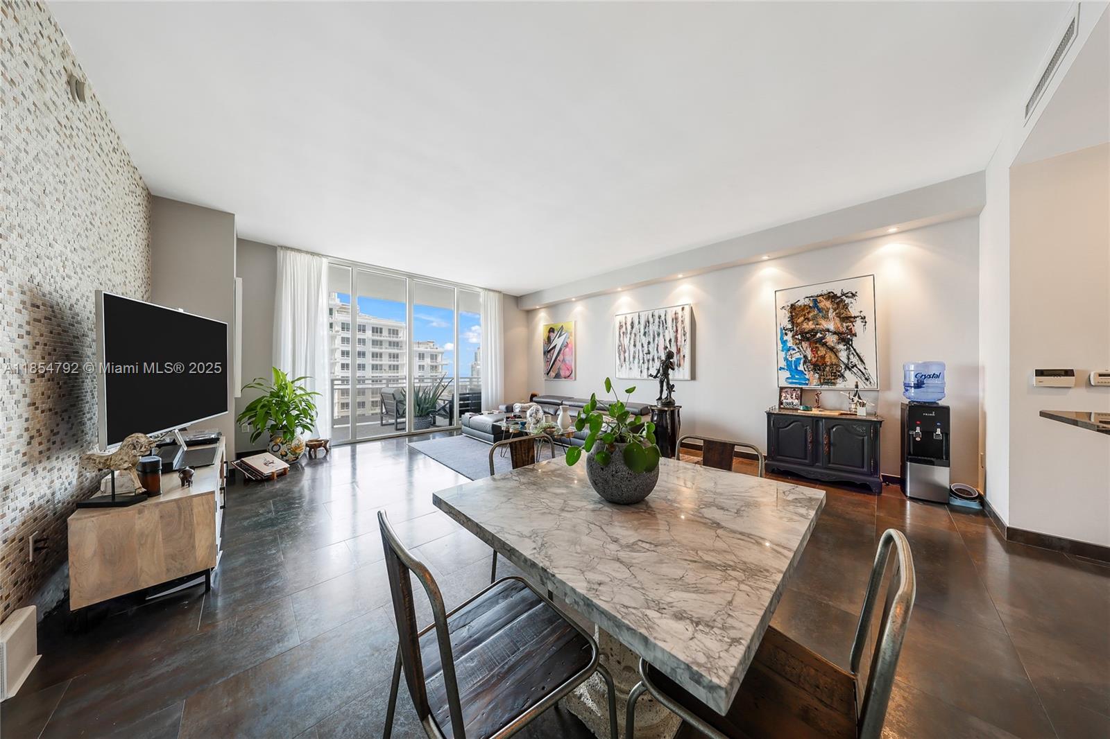 A modern living and dining area features a marble table, dark tile floors, and balcony access — 901 Brickell Key Blvd # 3002, Miami FL 33131, MIAMI, FL