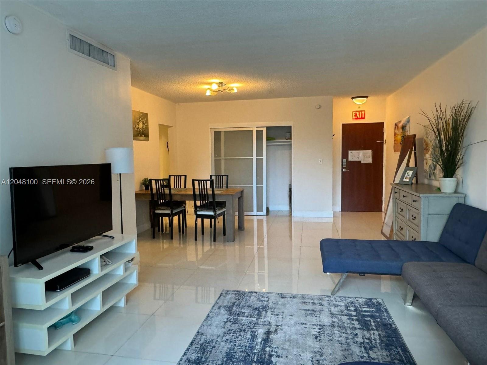 A living and dining area features white tile floors, a blue sofa, and a table — 3901 S Ocean Dr # 3U, Hollywood FL 33019, HOLLYWOOD, FL