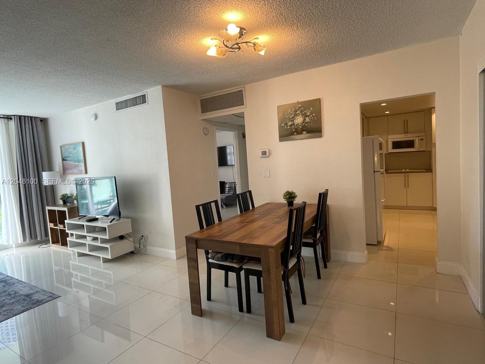 A dining area with a wooden table and chairs sits adjacent to a white kitchen — 3901 S Ocean Dr # 3U, Hollywood FL 33019, HOLLYWOOD, FL