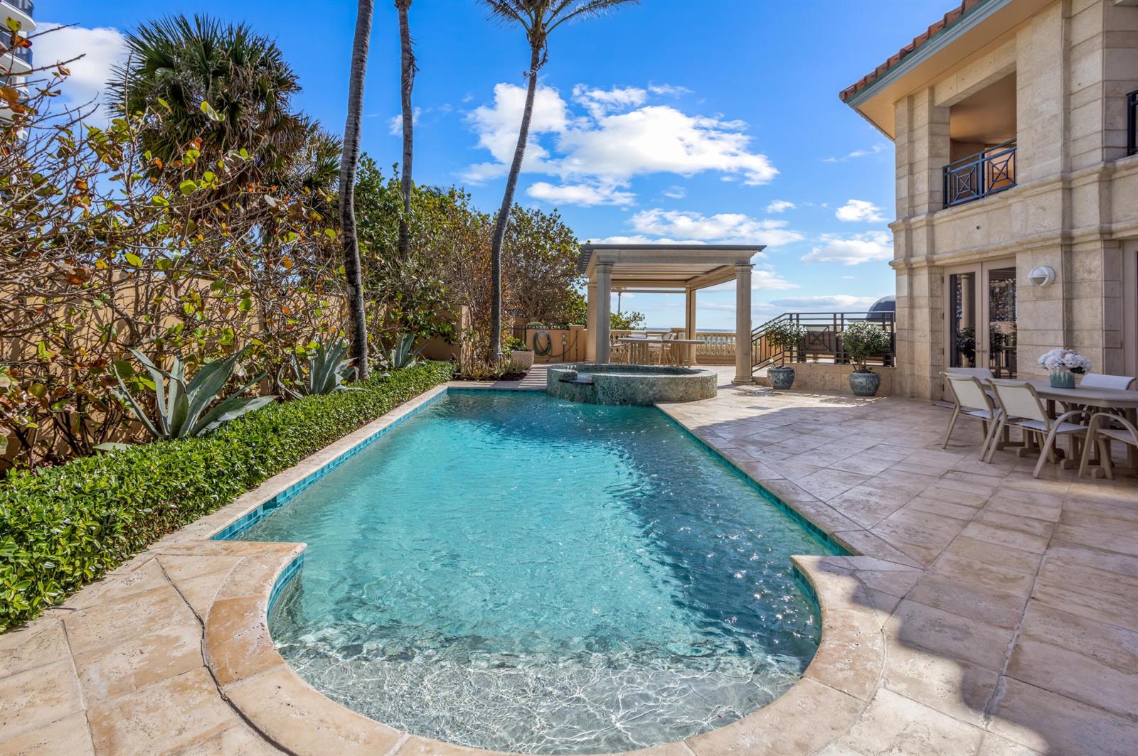 A swimming pool with a spa sits on a stone patio beside a multi-story house — 400 S Ocean Boulevard # 26, Boca Raton FL 33432, BOCA RATON, FL