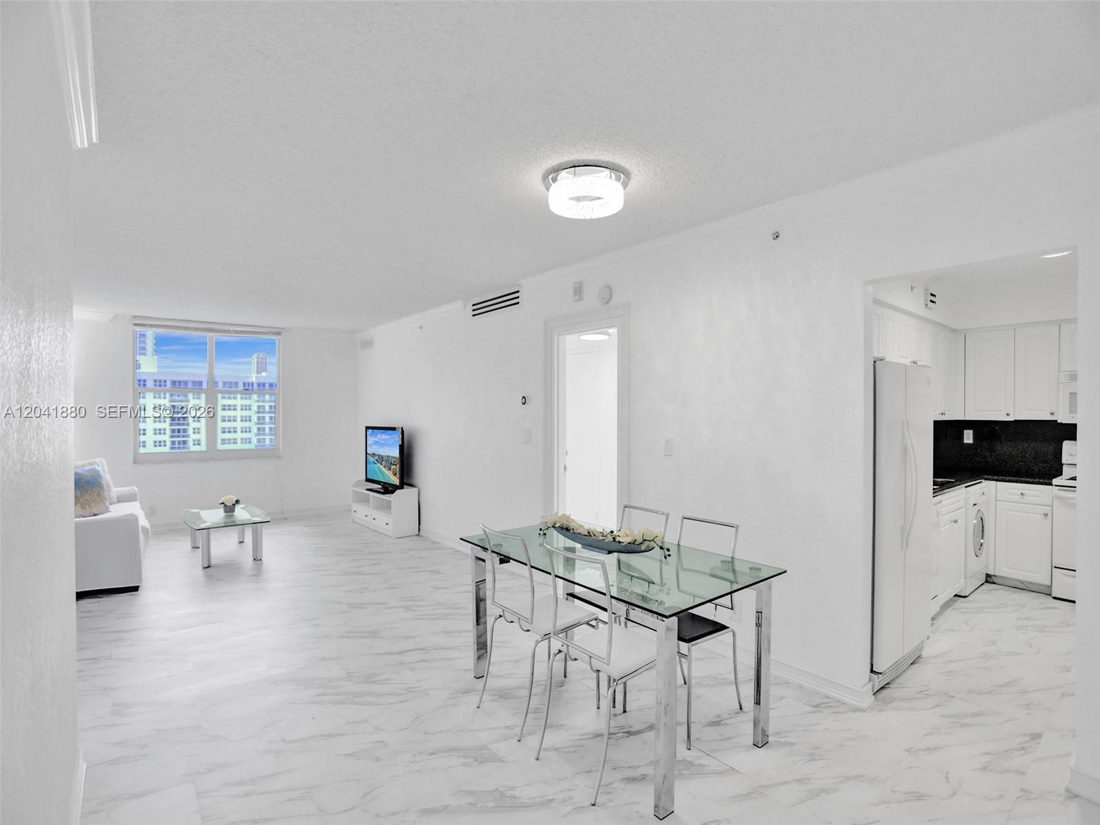 An open-concept living and dining area features white marble-style flooring and a modern kitchen — 2501 S Ocean Dr, Hollywood FL 33019, HOLLYWOOD, FL