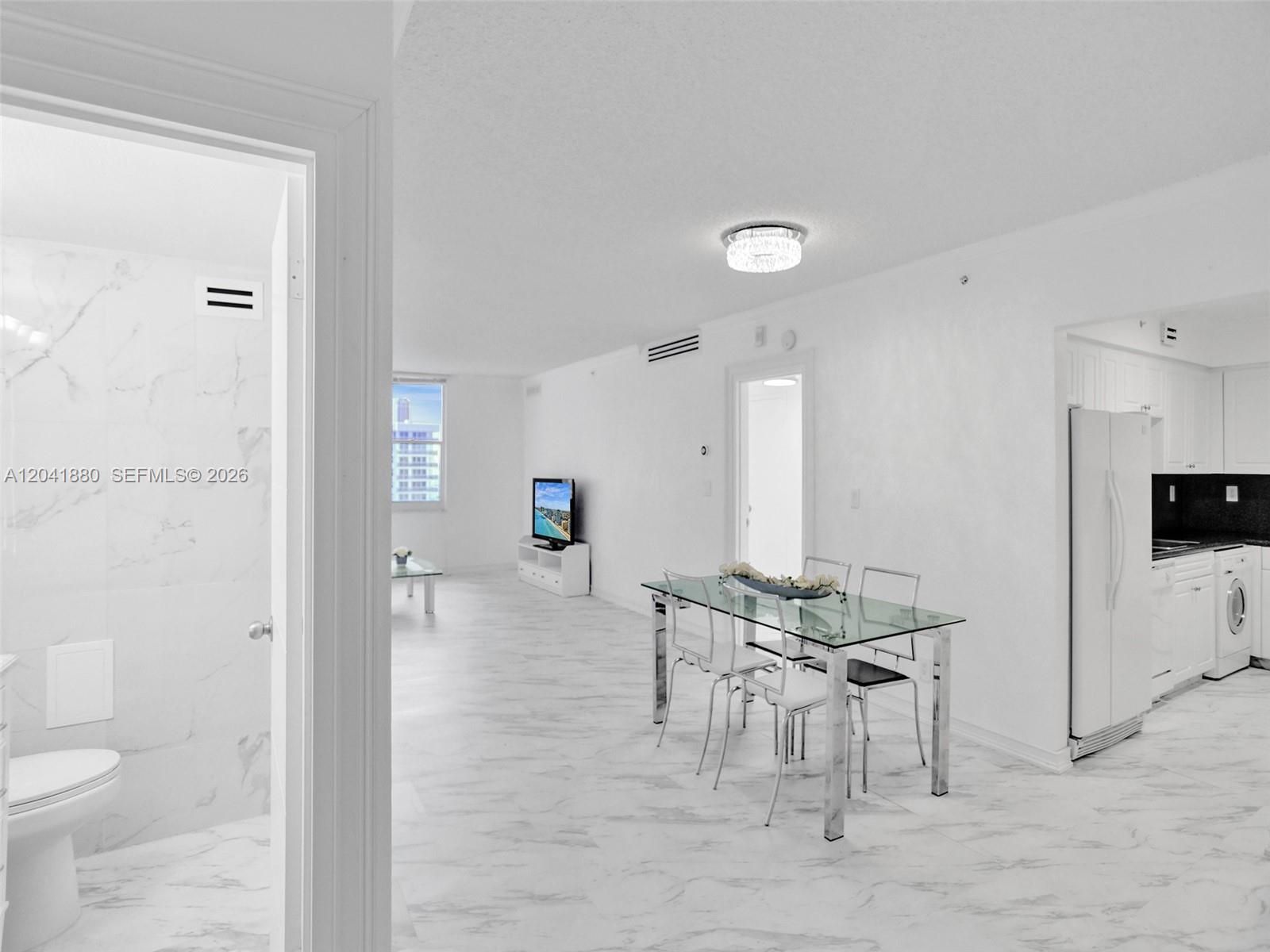 A bright, open-concept living and dining area features white marble-style flooring and a glass table — 2501 S Ocean Dr, Hollywood FL 33019, HOLLYWOOD, FL
