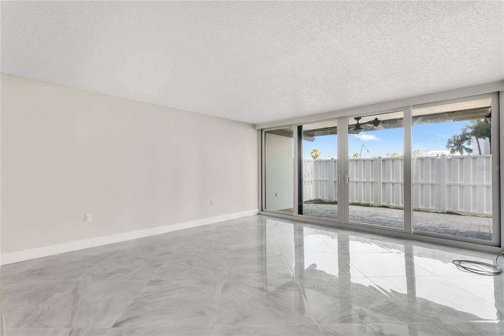 An empty room with light gray marble-look tile flooring and large sliding glass patio doors — 450 TREASURE ISLAND CAUSEWAY UNIT 104, TREASURE ISLAND, FL
