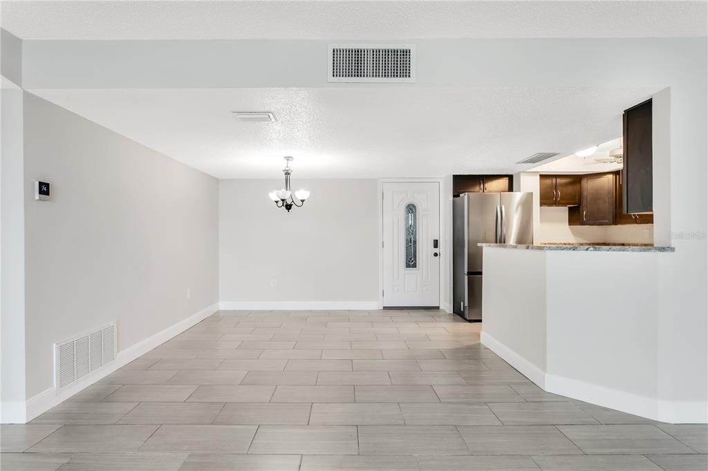A dining area with tile flooring leads to an open kitchen with dark wood cabinets — 450 TREASURE ISLAND CAUSEWAY UNIT 104, TREASURE ISLAND, FL