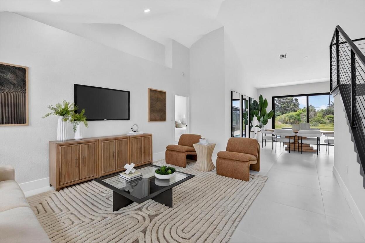 A modern living room features a wooden console, two brown chairs, and a glass coffee table — 7548 Fairway Trail, Boca Raton FL 33487, BOCA RATON, FL