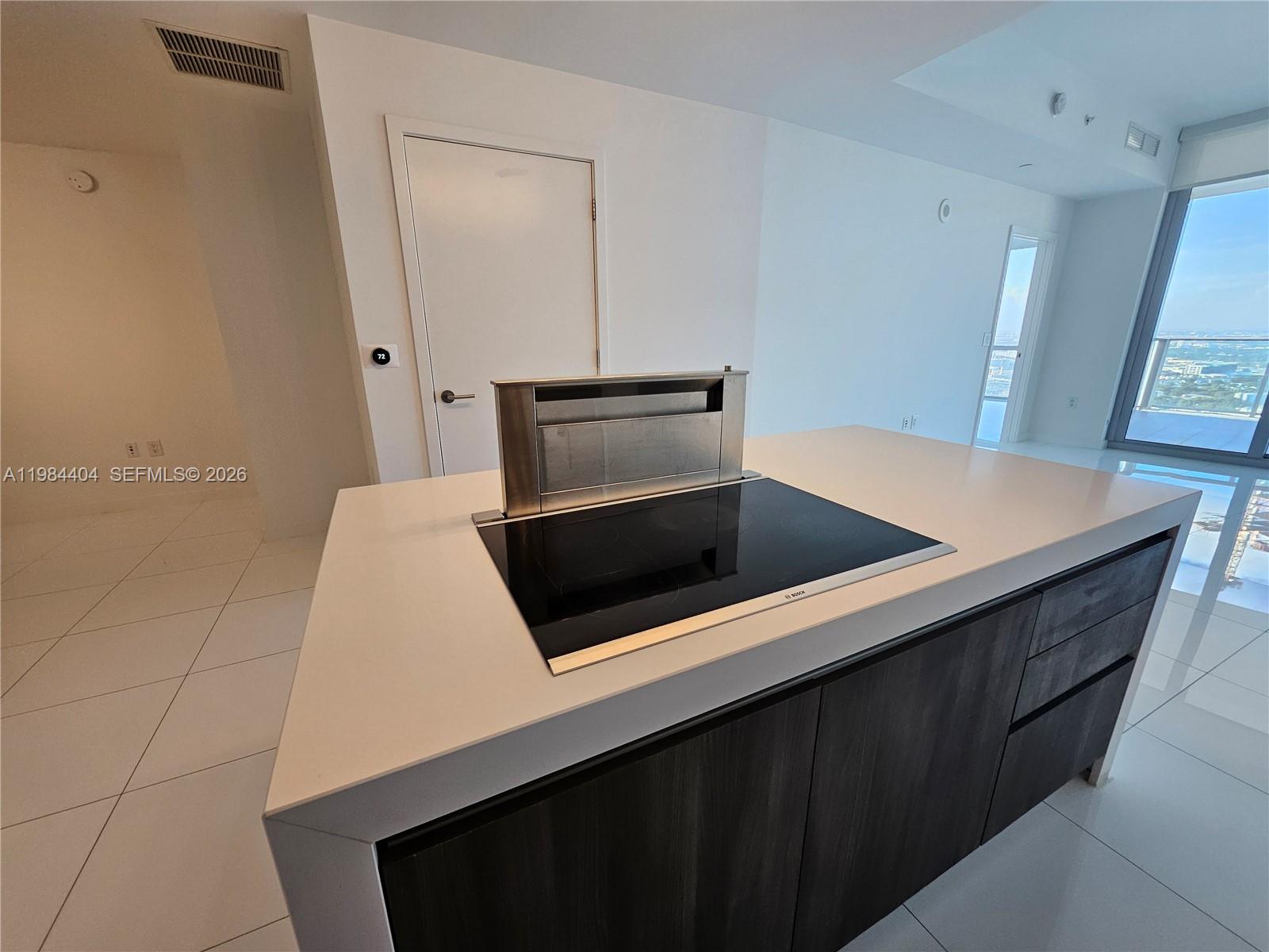 A kitchen island features a black induction cooktop with a retractable downdraft vent — 851 NE 1st Ave # 4000, Miami FL 33132, MIAMI, FL