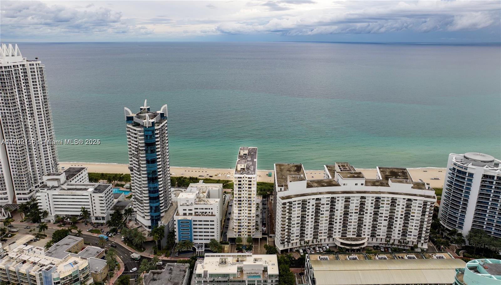 An aerial view shows several high-rise buildings situated along a sandy beach and ocean — 6061 Collins Ave # 7D, Miami Beach FL 33140, MIAMI BEACH, FL