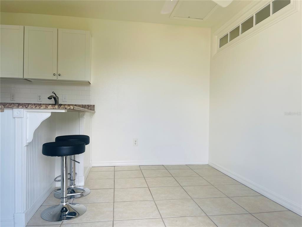 A kitchen area features white cabinets, a granite countertop, two bar stools, and tiled flooring — 506 CARIBBEAN DRIVE UNIT B, DAVENPORT, FL
