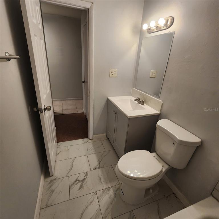 A bathroom features a white vanity, a toilet, and light-colored tile flooring — 1205 E 99TH AVENUE, TAMPA, FL