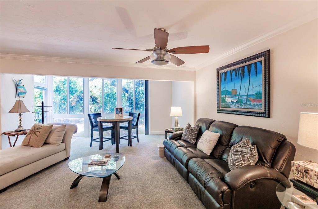A living room features a dark leather sofa, a glass coffee table, and a dining area — 1205 E PEPPERTREE DRIVE UNIT 232, SARASOTA, FL