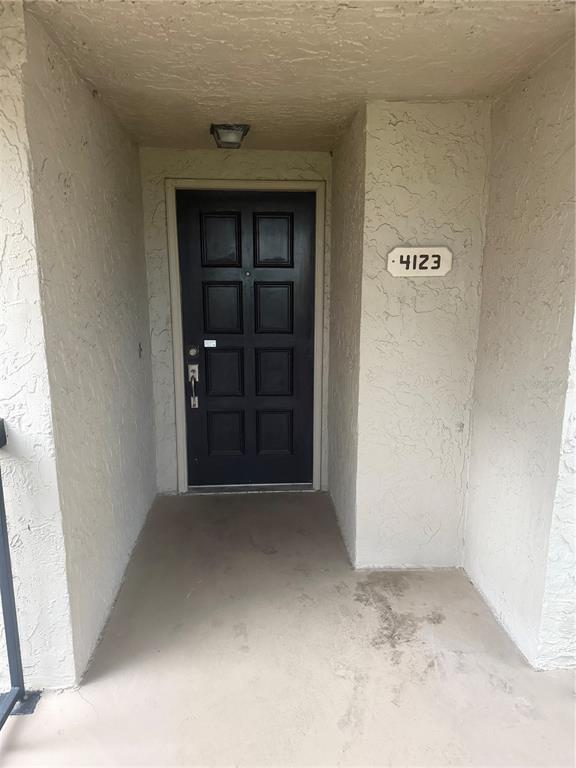 A dark-colored front door with eight panels is recessed within a stucco entryway — 4123 PLAYER CIR UNIT 509, ORLANDO, FL