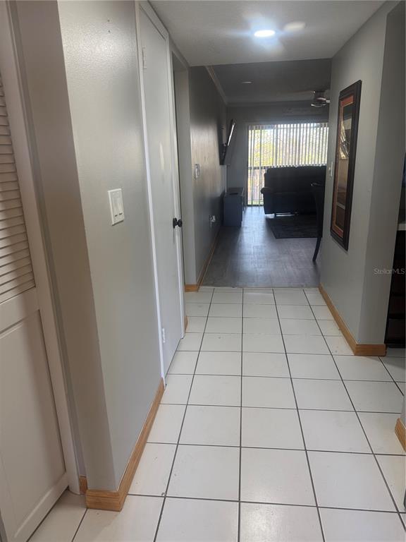 A tiled hallway leads toward a living area with a sofa and vertical blinds — 4123 PLAYER CIR UNIT 509, ORLANDO, FL