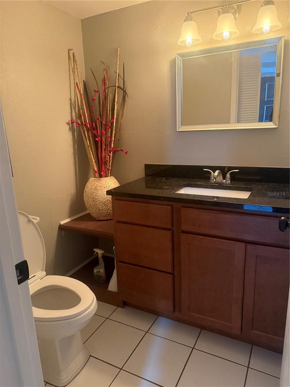A bathroom features a vanity with a dark countertop, a mirror, and a toilet — 4123 PLAYER CIR UNIT 509, ORLANDO, FL