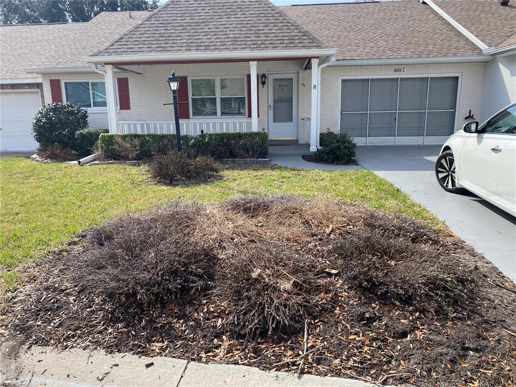 A single-story brick house features a front porch, a garage, and a landscaped front yard — 8666 SW 92ND LANE UNIT C, OCALA, FL