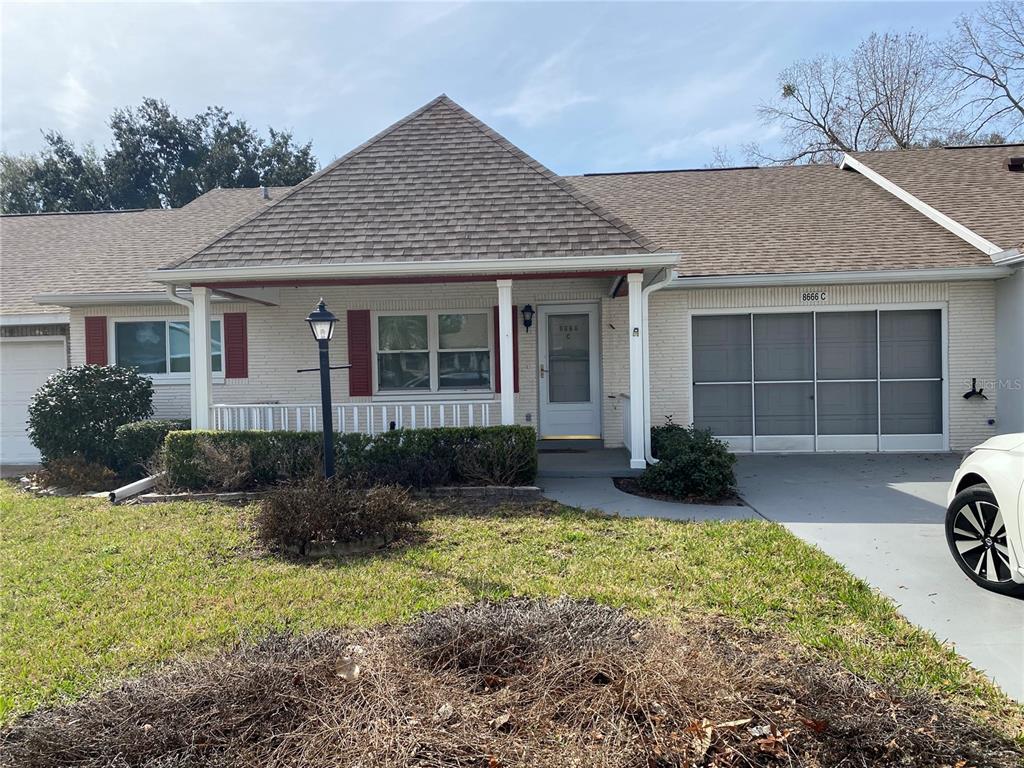 A single-story brick house with a covered porch, a front lawn, and a garage — 8666 SW 92ND LANE UNIT C, OCALA, FL