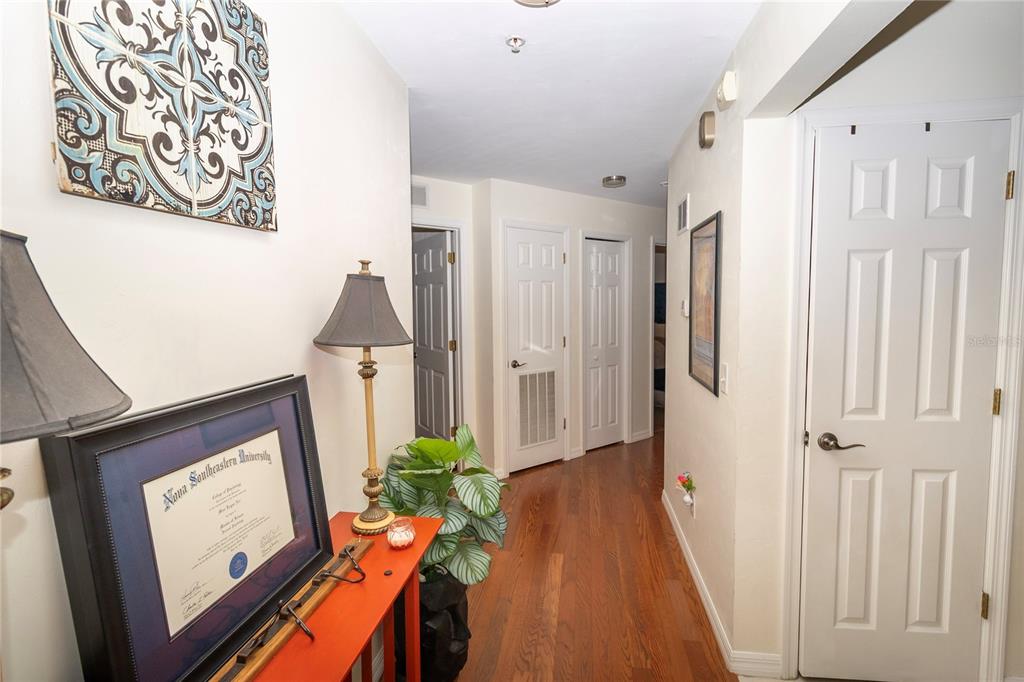 A hallway with hardwood floors, white doors, and a red console table with a lamp — 4215 SW 31ST DRIVE UNIT 201, GAINESVILLE, FL