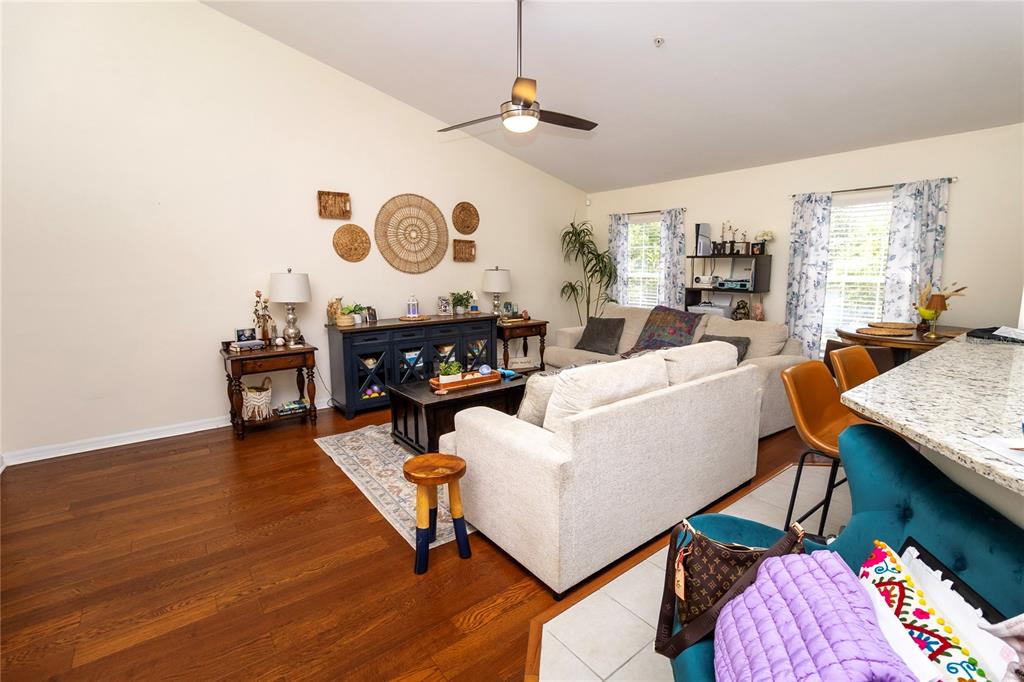 A living room features hardwood floors, a beige sofa, and a dark wood media console — 4215 SW 31ST DRIVE UNIT 201, GAINESVILLE, FL