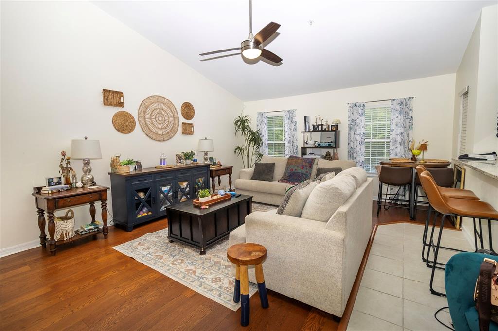 A living room features hardwood floors, a beige sofa, a dark console table, and a ceiling fan — 4215 SW 31ST DRIVE UNIT 201, GAINESVILLE, FL