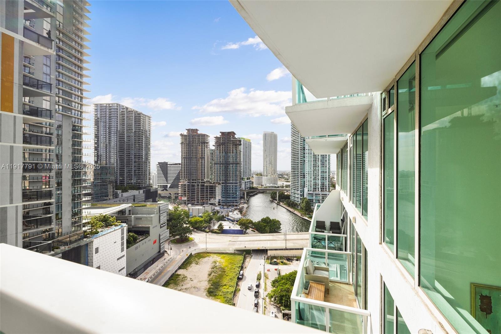 A high-rise balcony view overlooks a city skyline, a river, and nearby construction sites — 41 SE 5th St # 1210, Miami FL 33131, MIAMI, FL