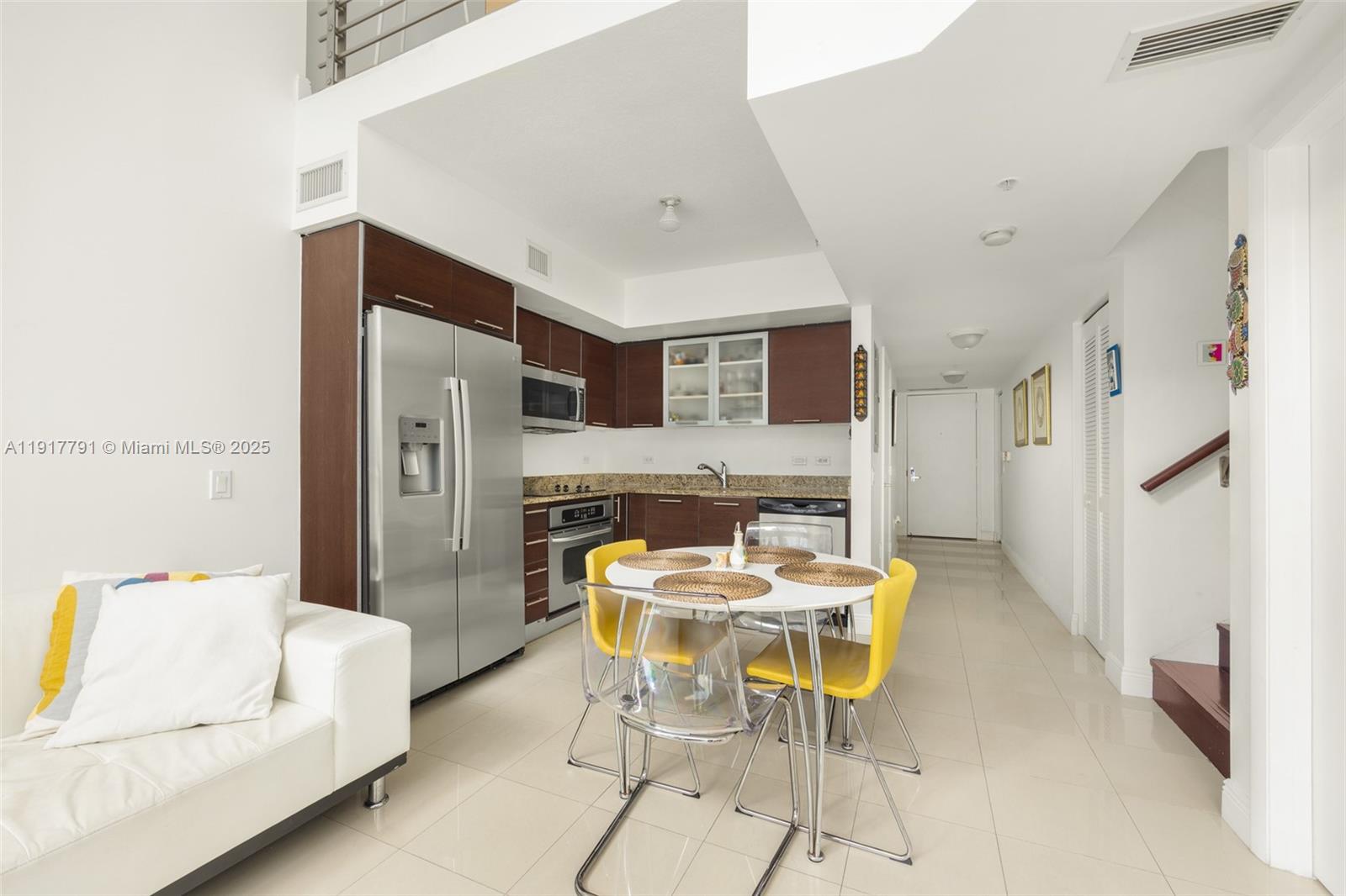 A kitchen with stainless steel appliances and a dining table sits beside a white sofa — 41 SE 5th St # 1210, Miami FL 33131, MIAMI, FL