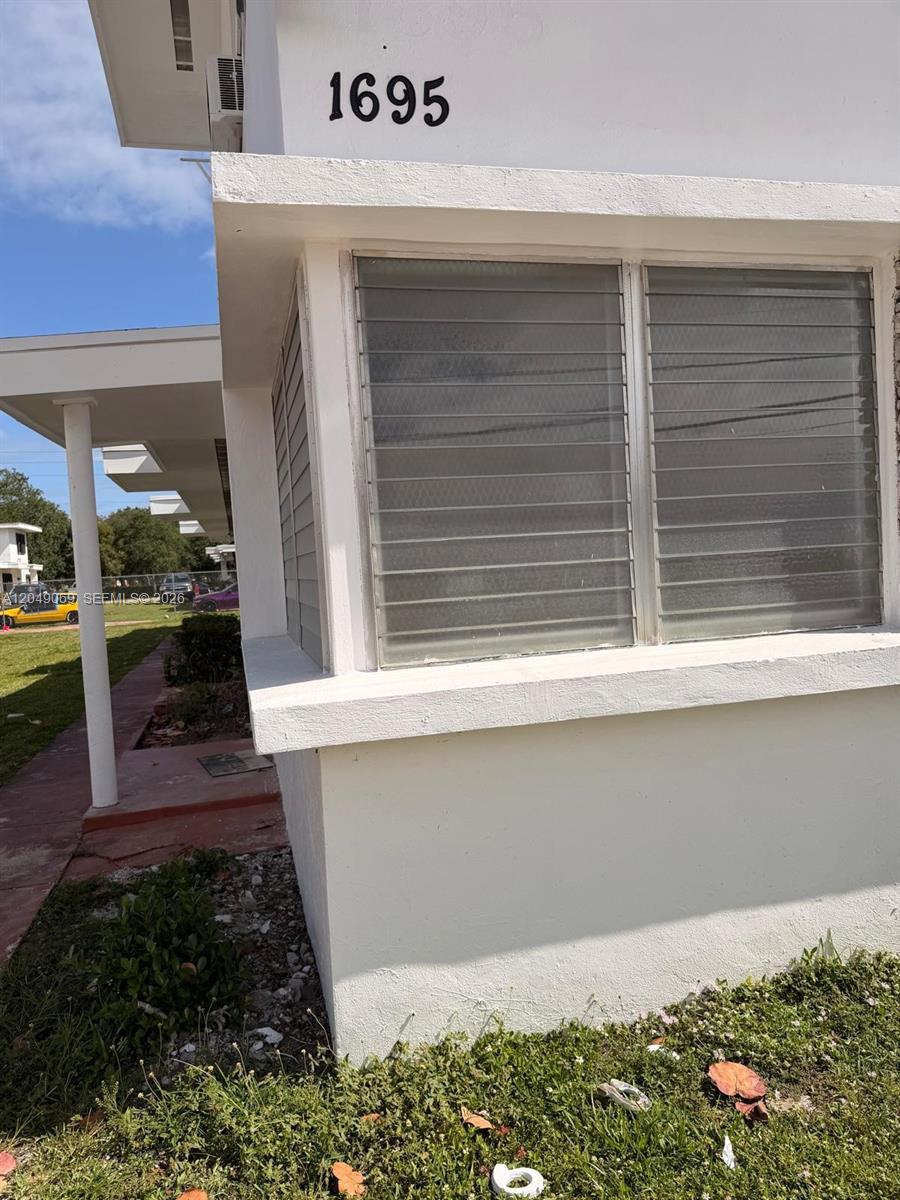 A white exterior wall features the house number 1695 and two louvered glass windows — 1695 NE 150th St # 3, Miami FL 33181, MIAMI, FL