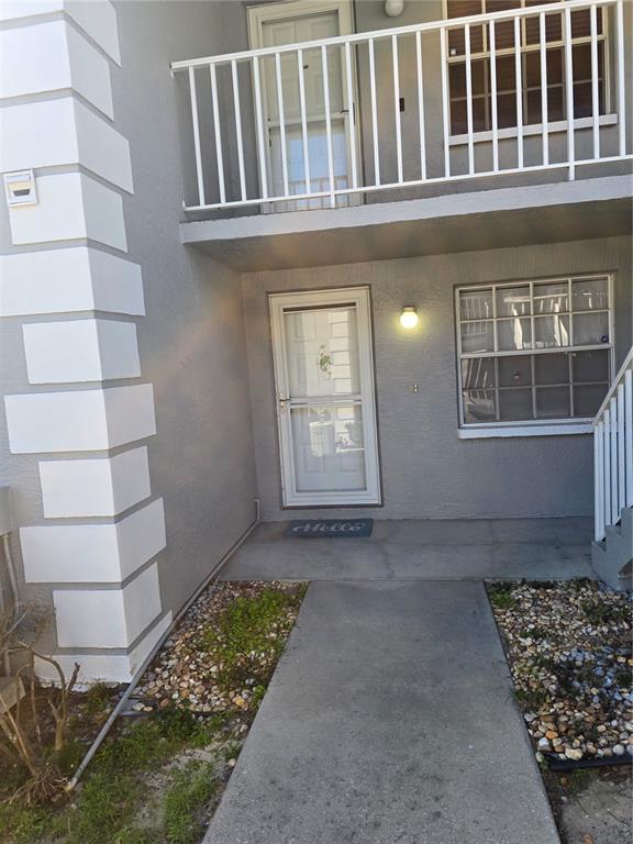A concrete walkway leads to the front entrance of a two-story gray stucco building — 12133 SPARTAN WAY UNIT 102, HUDSON, FL