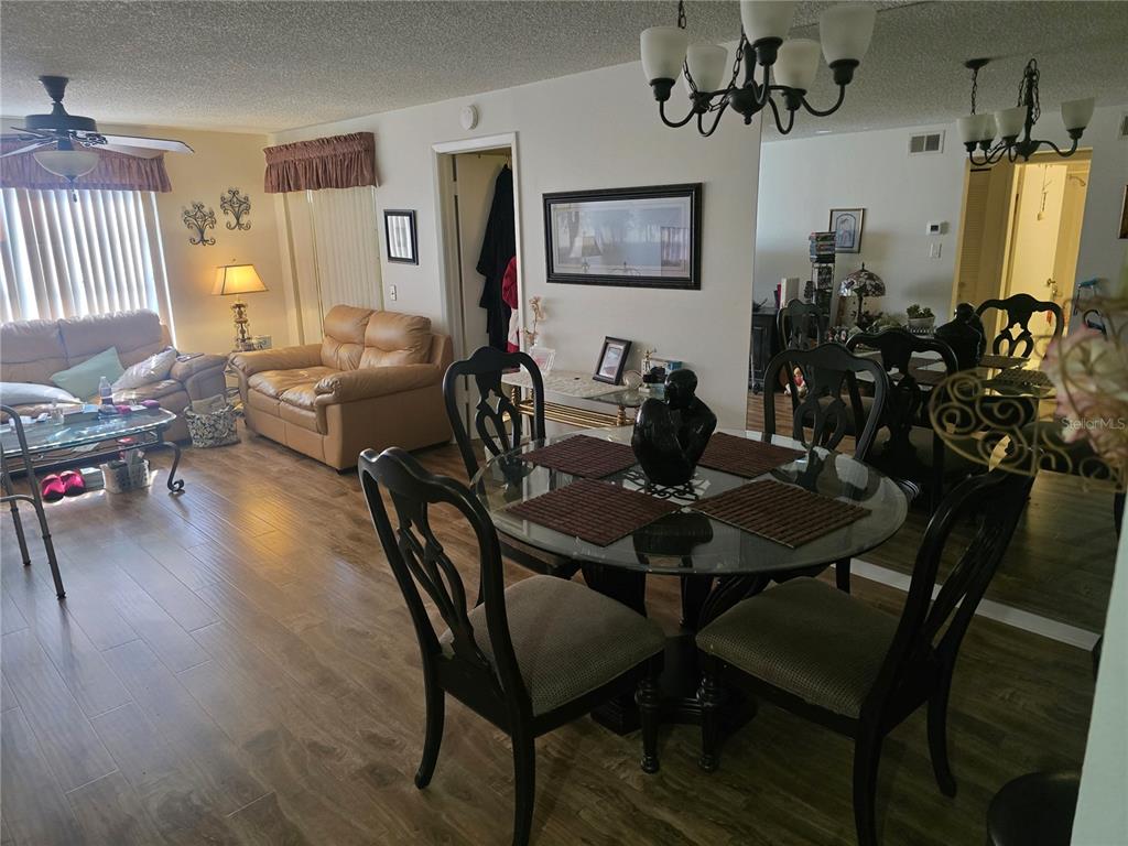 A dining area with a glass table and chairs sits adjacent to a living room — 12133 SPARTAN WAY UNIT 102, HUDSON, FL