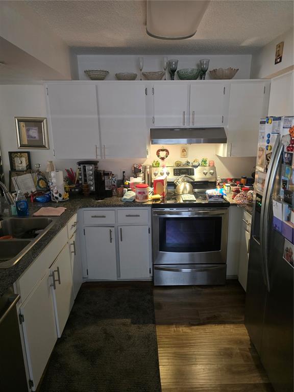 A kitchen with white cabinets, stainless steel appliances, and dark granite countertops — 12133 SPARTAN WAY UNIT 102, HUDSON, FL