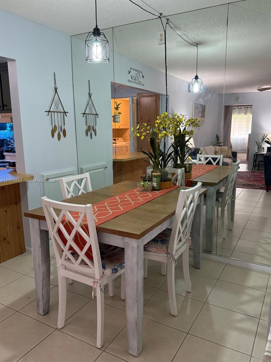 A dining area features a wooden table with white chairs, a mirrored wall, and pendant lighting — 208 Pine Hov Cir # 2, Green Acres FL 33463, GREEN ACRES, FL