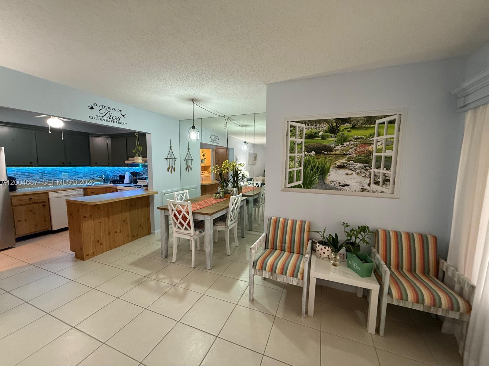A dining area and kitchen feature light blue walls, tiled floors, and a mirrored wall — 208 Pine Hov Cir # 2, Green Acres FL 33463, GREEN ACRES, FL
