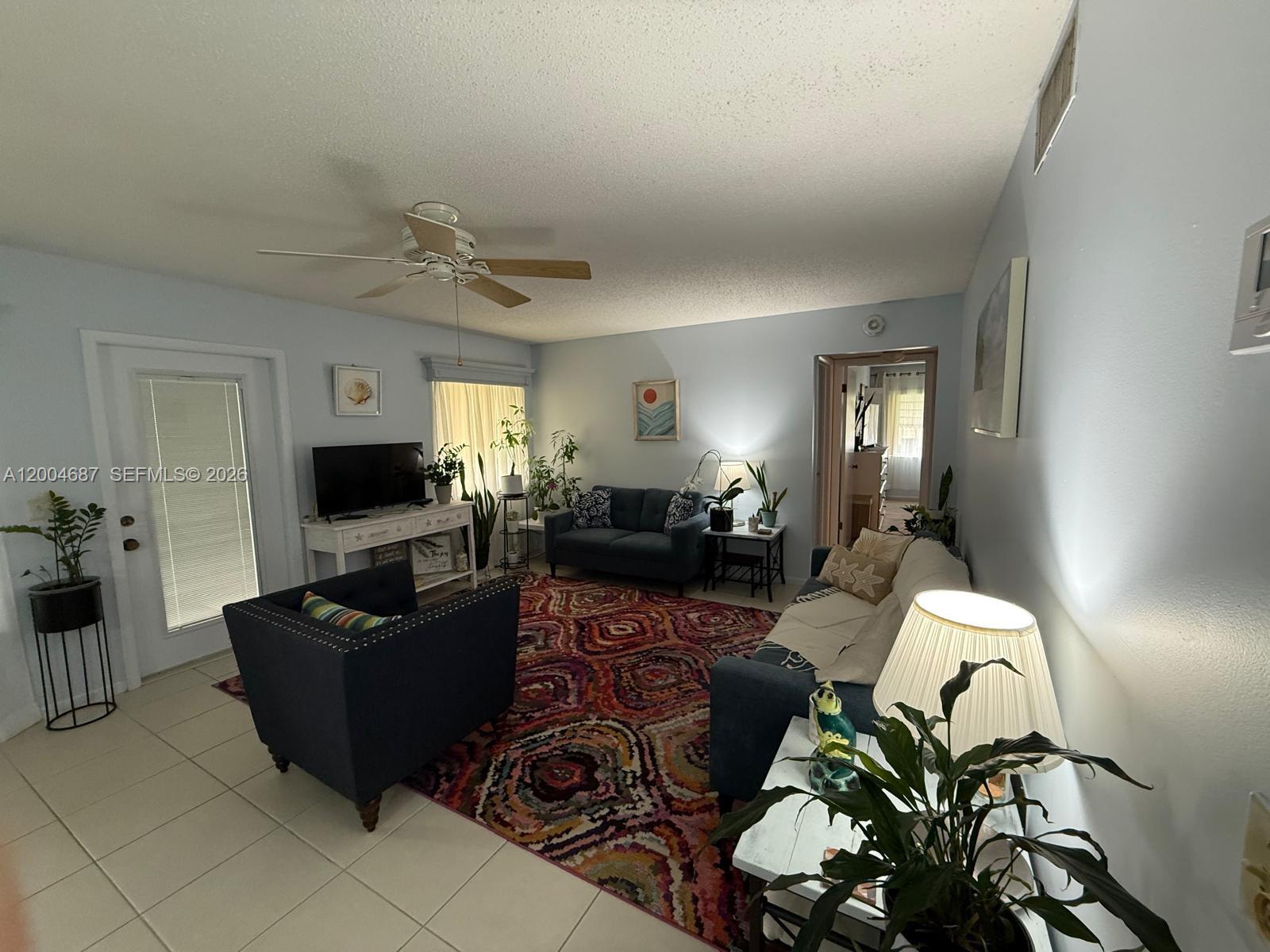 A living room features a patterned area rug, blue seating, and a ceiling fan — 208 Pine Hov Cir # 2, Green Acres FL 33463, GREEN ACRES, FL