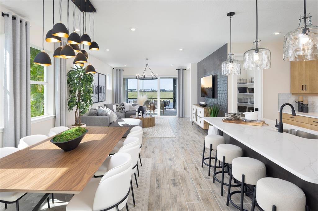 An open-concept living area features a dining table, kitchen island with stools, and sliding doors — 11292 BOUNDLESS TERRACE, VENICE, FL